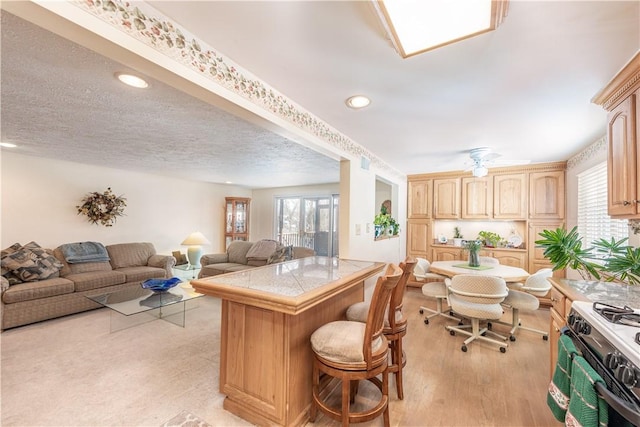 kitchen with tile counters, light brown cabinets, a healthy amount of sunlight, and a breakfast bar