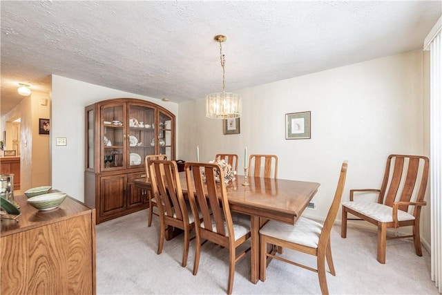 carpeted dining area with a notable chandelier and a textured ceiling