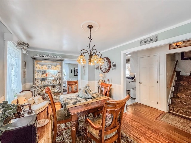 dining space featuring ornamental molding, light wood-type flooring, and a notable chandelier