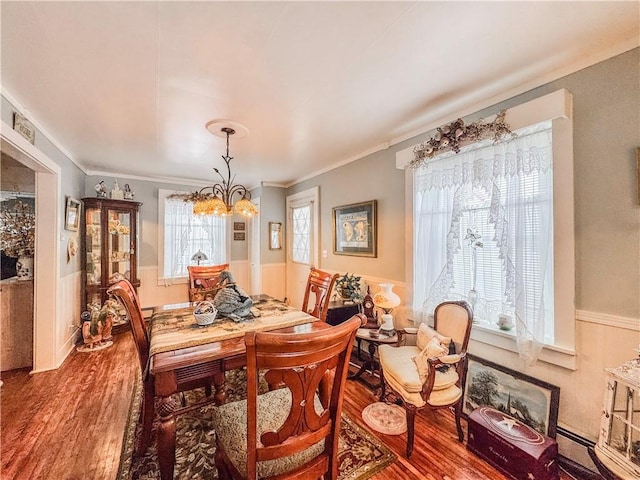 dining space featuring hardwood / wood-style flooring, crown molding, and a chandelier