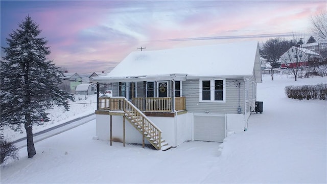 snow covered back of property with a garage