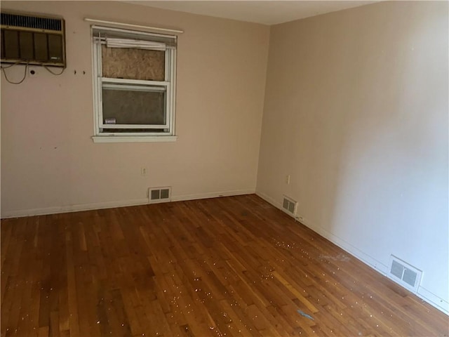 spare room featuring a wall mounted air conditioner and wood-type flooring