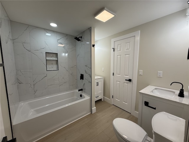 full bathroom with vanity, wood-type flooring, tiled shower / bath combo, and toilet