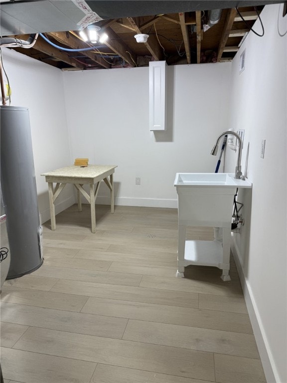 laundry room featuring light wood-type flooring and gas water heater