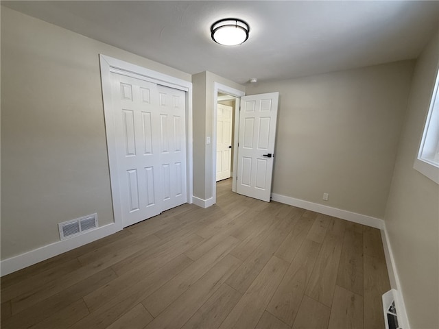 unfurnished bedroom with light wood-type flooring and a closet