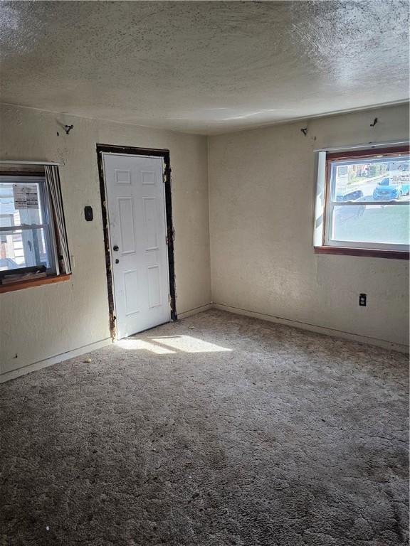 carpeted spare room with a textured ceiling