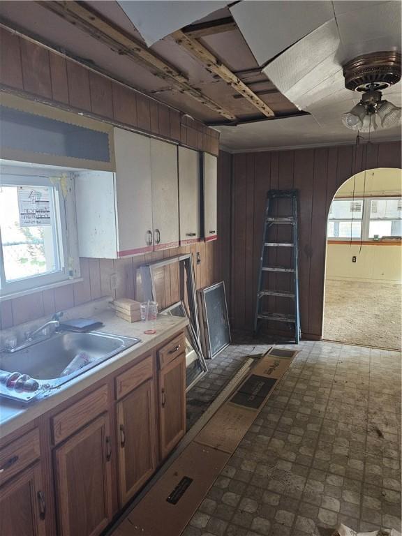 kitchen with ceiling fan, sink, and wooden walls