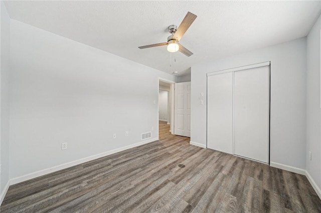 unfurnished bedroom featuring dark hardwood / wood-style flooring, ceiling fan, and a closet