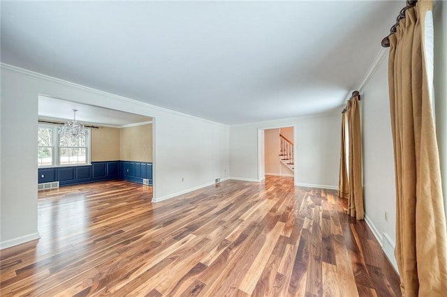 unfurnished room with crown molding, a chandelier, and hardwood / wood-style flooring