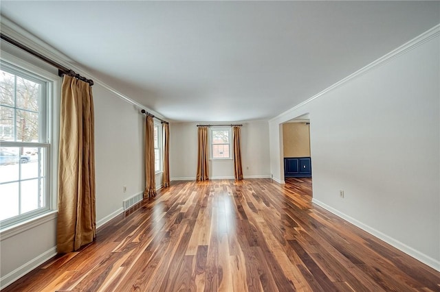 empty room with ornamental molding, dark wood-type flooring, and a wealth of natural light