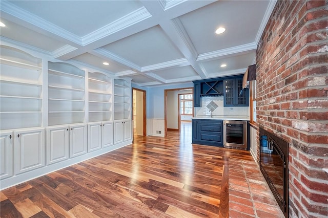 bar with blue cabinetry, hardwood / wood-style floors, built in features, and beverage cooler