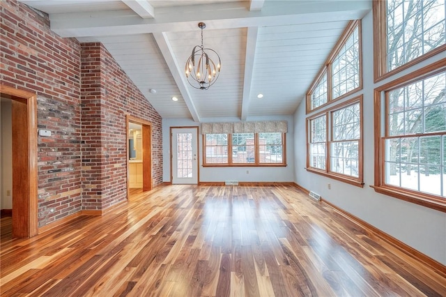 unfurnished living room featuring beam ceiling, hardwood / wood-style flooring, brick wall, and a notable chandelier