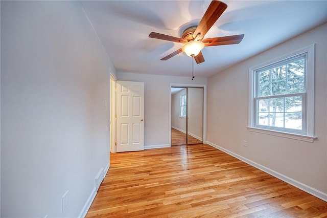 unfurnished bedroom with ceiling fan, light wood-type flooring, and a closet