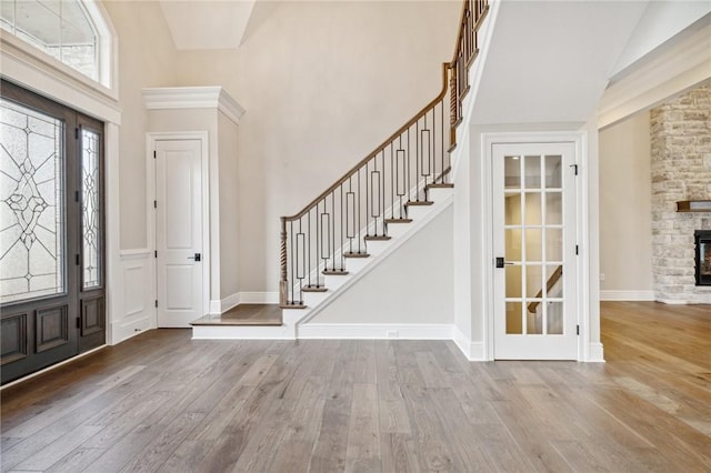 entryway with a fireplace, light hardwood / wood-style flooring, and high vaulted ceiling