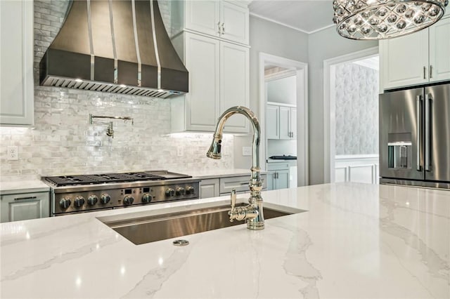 kitchen with custom exhaust hood, sink, decorative backsplash, light stone countertops, and stainless steel fridge with ice dispenser