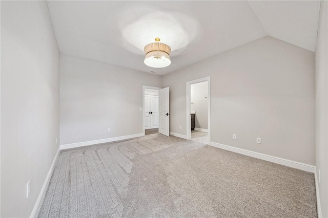 unfurnished bedroom with carpet flooring, ensuite bath, and lofted ceiling