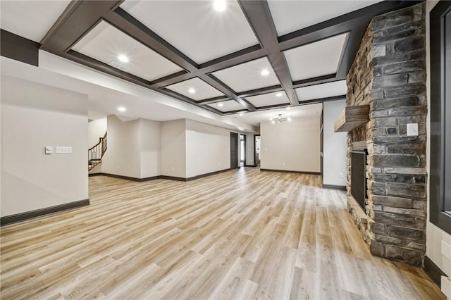 unfurnished living room with coffered ceiling, a fireplace, beamed ceiling, and light hardwood / wood-style flooring