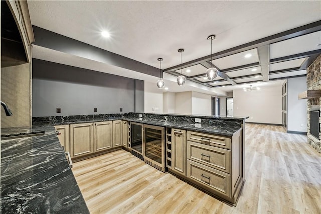 kitchen featuring beam ceiling, dark stone countertops, kitchen peninsula, and pendant lighting