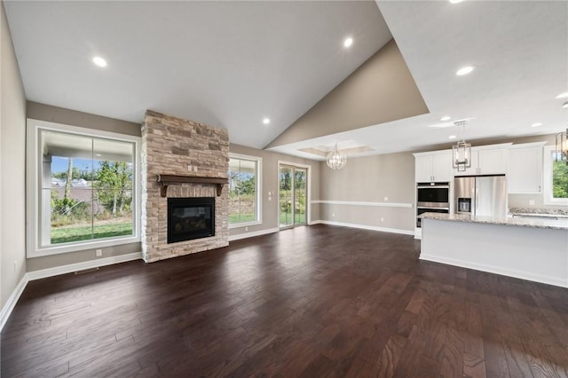 unfurnished living room featuring dark hardwood / wood-style flooring, a stone fireplace, and high vaulted ceiling