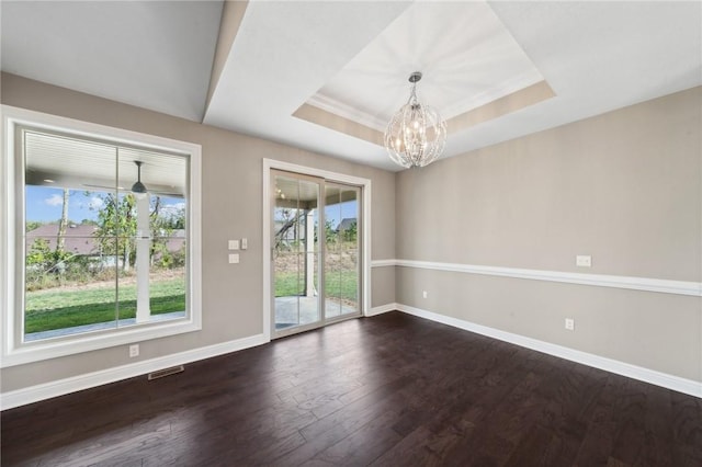 unfurnished room with dark hardwood / wood-style flooring, a tray ceiling, and a notable chandelier