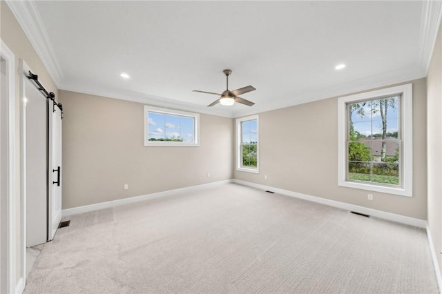 unfurnished bedroom with a barn door, ceiling fan, light colored carpet, and ornamental molding