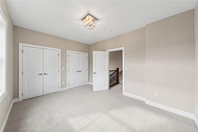 unfurnished bedroom featuring light colored carpet and two closets