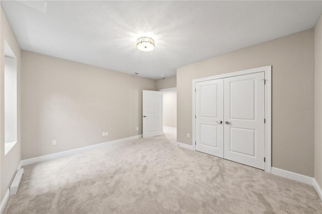 unfurnished bedroom with light colored carpet and a closet