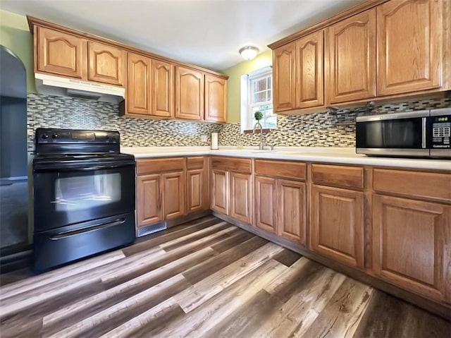 kitchen with black electric range, dark hardwood / wood-style floors, tasteful backsplash, and sink