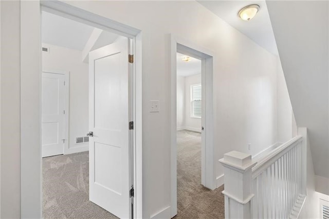 hall featuring lofted ceiling and light carpet