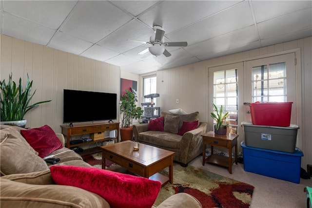 living room featuring carpet flooring, ceiling fan, and a drop ceiling