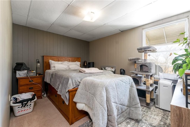 bedroom with light carpet and wood walls