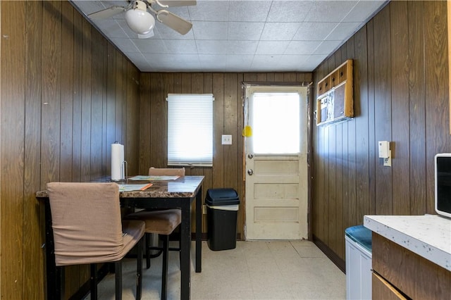 dining area featuring ceiling fan and wood walls