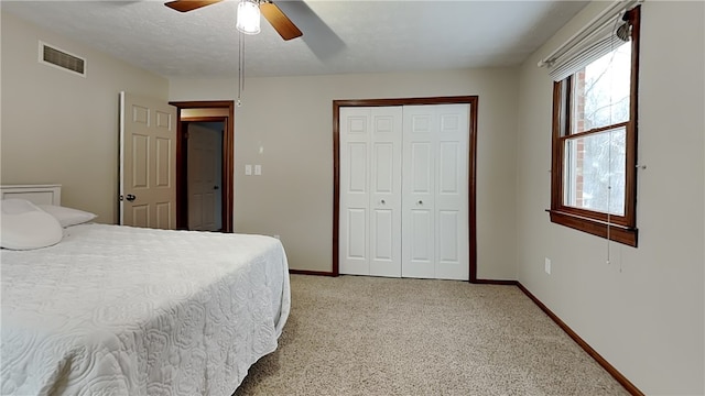 carpeted bedroom with ceiling fan, a closet, and a textured ceiling