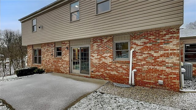 snow covered property featuring cooling unit and a patio area