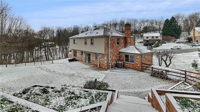 snow covered house featuring central AC unit