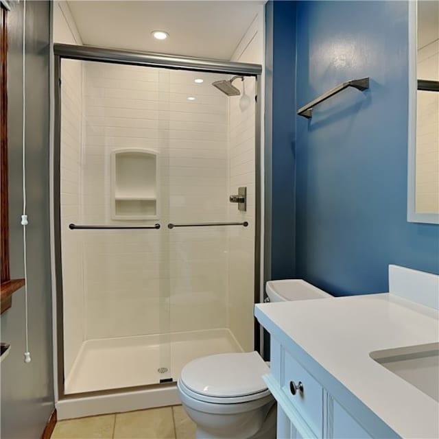 bathroom with tile patterned flooring, vanity, an enclosed shower, and toilet