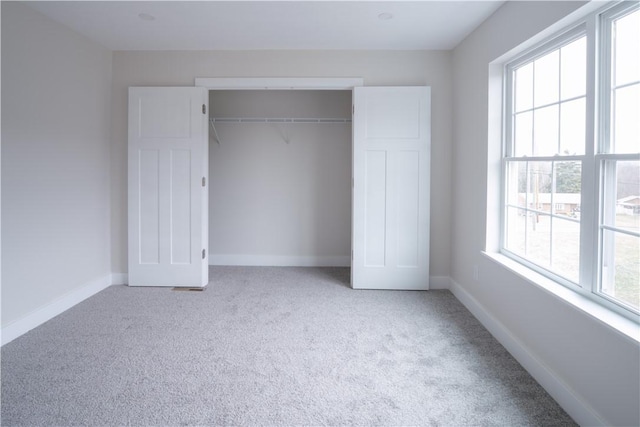 unfurnished bedroom with baseboards, a closet, and light colored carpet