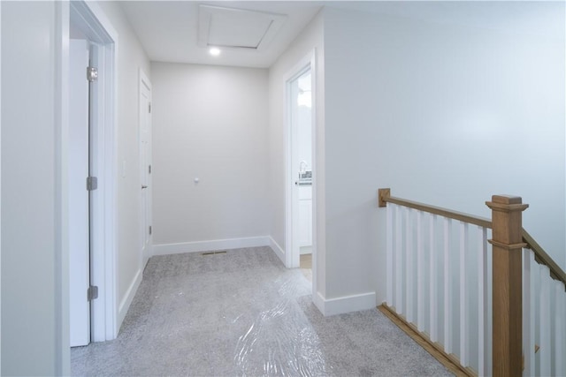 corridor featuring attic access, baseboards, and an upstairs landing