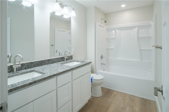 full bath with wood finished floors, tub / shower combination, a sink, and toilet