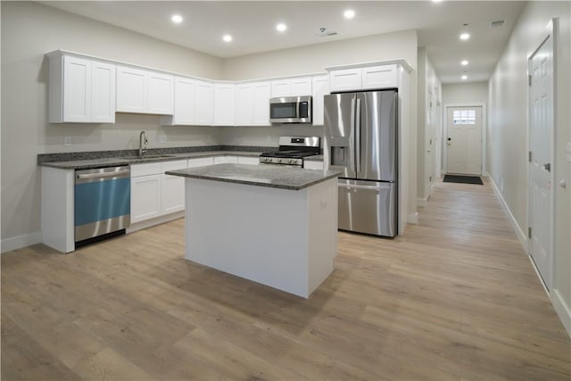 kitchen with light wood finished floors, white cabinetry, a kitchen island, and appliances with stainless steel finishes