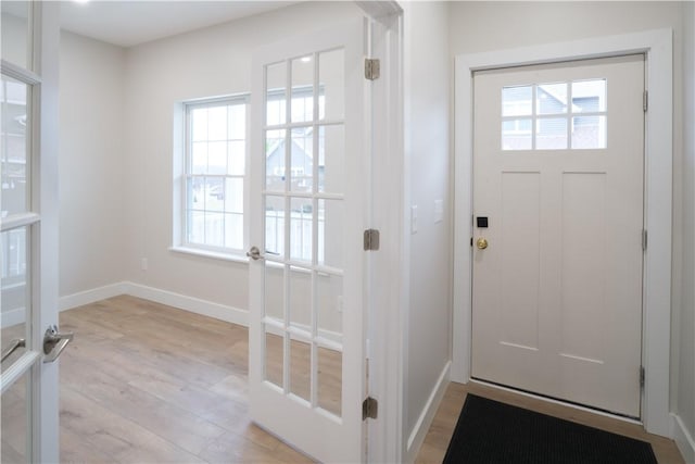 doorway to outside with light wood-style flooring and baseboards