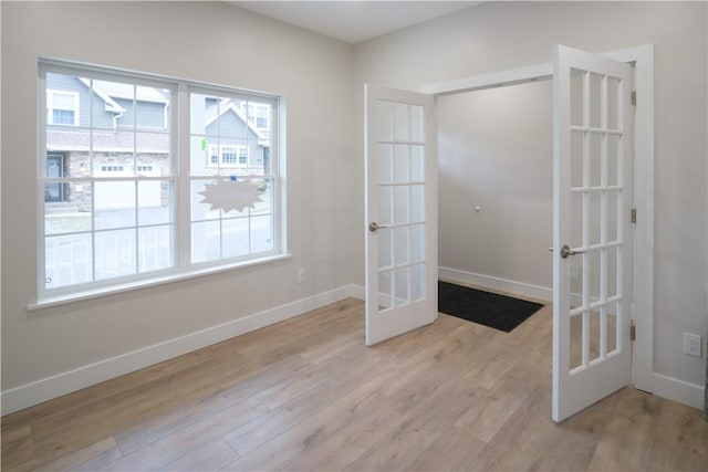 spare room featuring light wood-style flooring, baseboards, and french doors