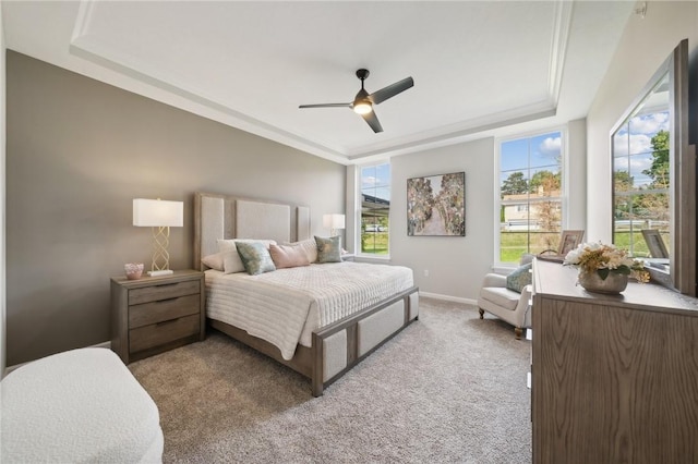 carpeted bedroom with a tray ceiling and ceiling fan