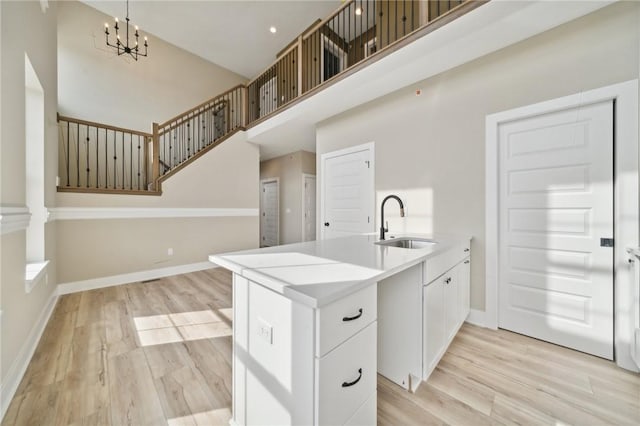 kitchen featuring kitchen peninsula, white cabinetry, sink, and light wood-type flooring