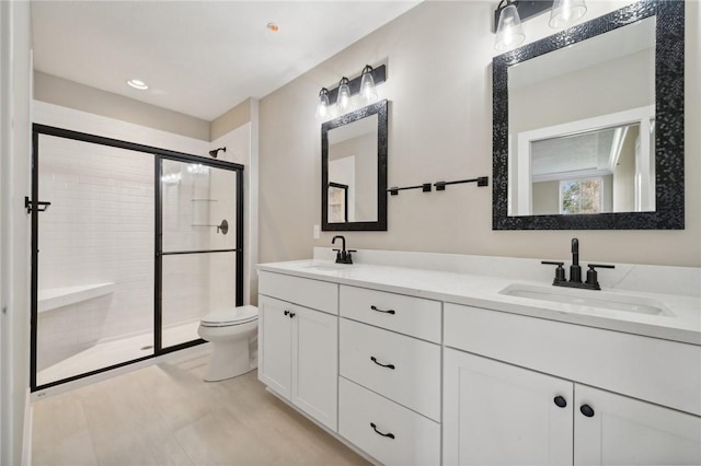 bathroom featuring vanity, a shower with shower door, and toilet