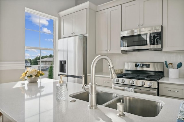 kitchen with light stone countertops, decorative backsplash, stainless steel appliances, and sink