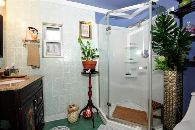 bathroom featuring vanity, an enclosed shower, and tile walls