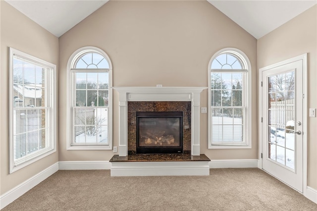 unfurnished living room with light carpet, a high end fireplace, and vaulted ceiling