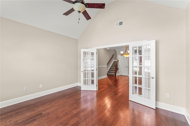 empty room with french doors, ceiling fan with notable chandelier, dark hardwood / wood-style floors, and high vaulted ceiling