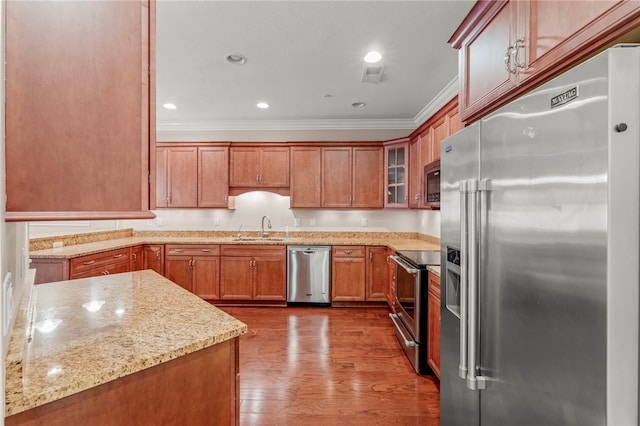 kitchen featuring light stone counters, ornamental molding, stainless steel appliances, sink, and hardwood / wood-style flooring